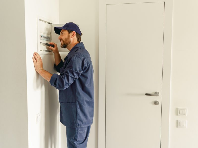 Professional male electrician inspect and repairing electrical systems in houses using a screwdriver